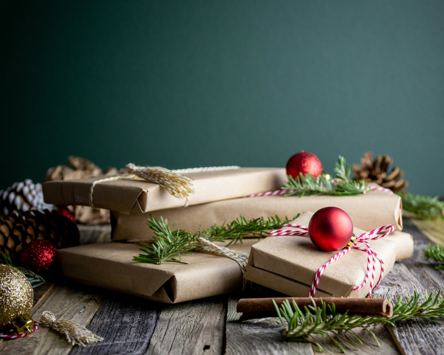Rustic Christmas gifts on a wooden table with pine sprigs and pinecones.